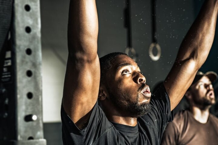 Man in gym with raised arms looking up